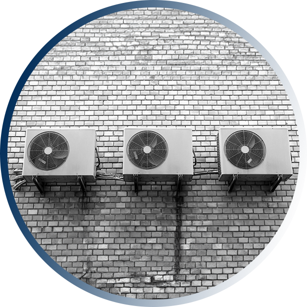 Three air conditioners mounted to the side of a brick wall.